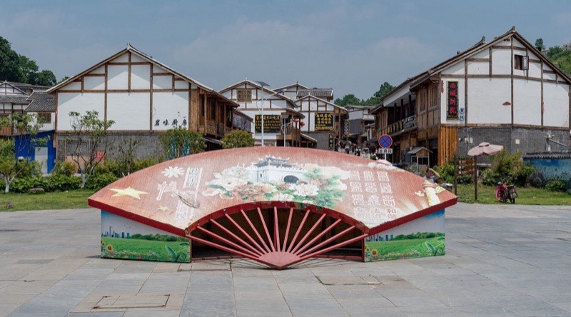青岩古镇：广场上的折扇雕塑和白墙木楼